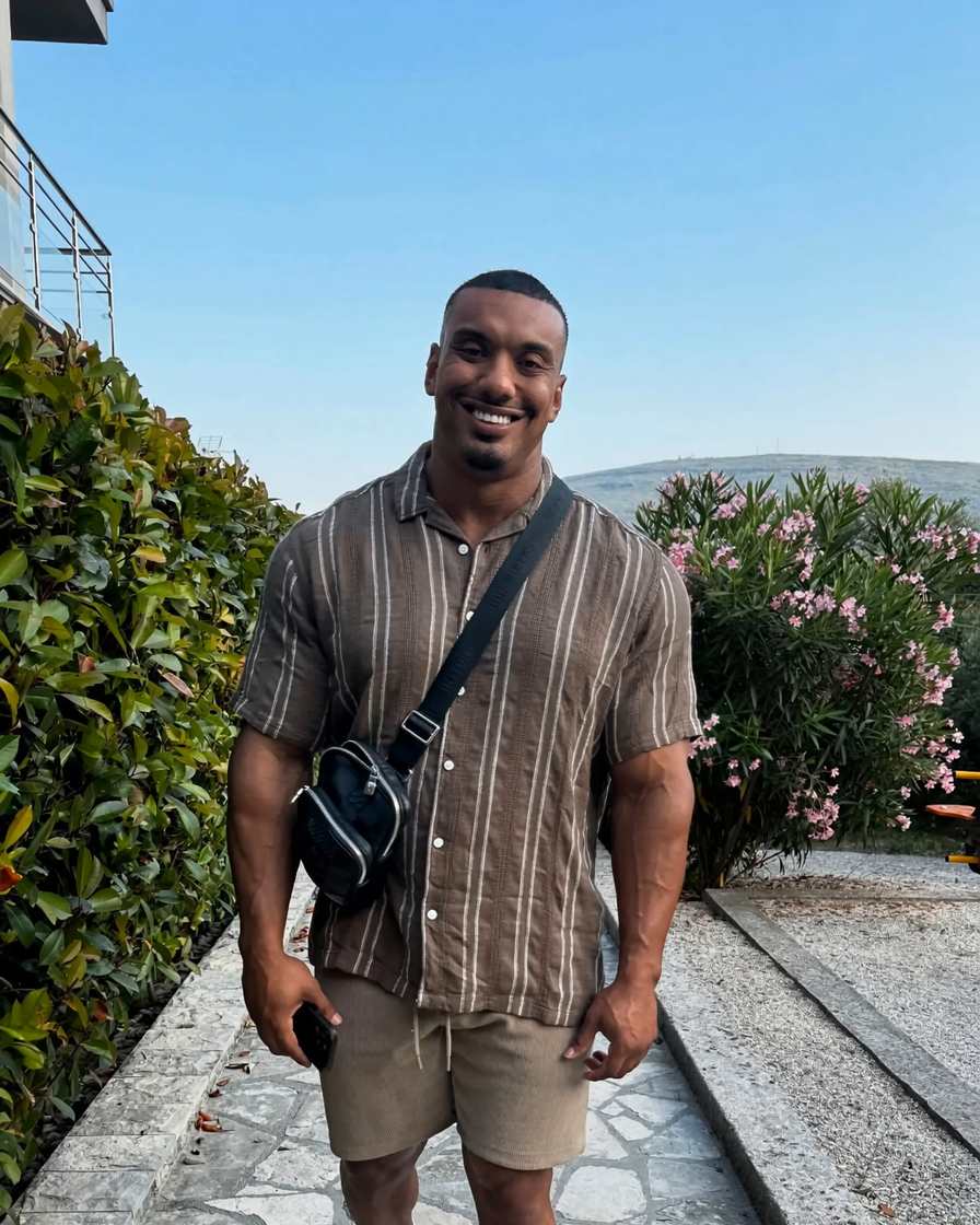 Larry Wheels smiling on a stone garden path in a brown striped shirt